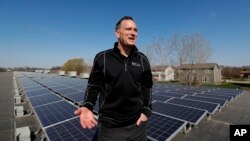 Todd Miller stands next to solar panels on the roof of his solar installation business in Ankeny, Iowa, April 15, 2019.
