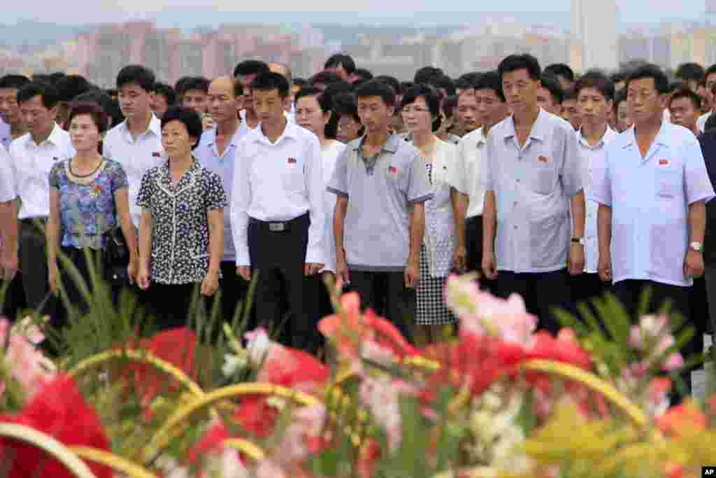 평양 만수대 언덕을 찾은 북한 주민들이 북한 김일성 주석 사망 23주기를 맞아 헌화한 후 묵념하고 있다.