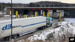 FILE - In this Wednesday, March 18, 2020 file photo, truck traffic from Canada waits to cross the border into the United States in Derby Line Vt. The U.S. will reopen its land borders to nonessential travel next month. (AP Photo/Wilson Ring, File)