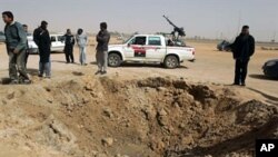 Libyan rebels inspect a crater caused by a bomb dropped by a plane in Ajdabiya on Mar 14 2011 as Libyan strongman Moamer Kadhafi's forces shelled rebel positions