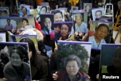 FILE - Students hold portraits of deceased former South Korean "comfort women" during a weekly anti-Japan rally in front of the Japanese Embassy in Seoul, South Korea, Dec. 30, 2015.