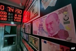 FILE - An oversized copy of a 200 Turkish lira banknote, featuring a photo of modern Turkey's founder Mustafa Kemal Ataturk, decorates a currency exchange shop in Istanbul.