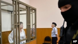 FILE - Jailed Ukrainian pilot Nadezhda Savchenko (L) stands in a defendant's cage during a court hearing in the town of Donetsk, Rostov-on-Don region, Russia, Sept. 29, 2015. 
