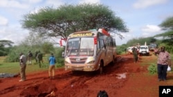 Kenyan security forces and others gather around the scene on an attack on a bus about 50 kilometers outside the town of Mandera, near the Somali border in northeastern Kenya, Nov. 22, 2014.