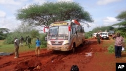 Kenyan security forces and others gather around the scene on an attack on a bus about 50 kilometers outside the town of Mandera, near the Somali border in northeastern Kenya, Nov. 22, 2014.