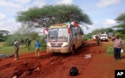FILE - Kenyan security forces and others gather around the scene on an attack on a bus about 50 kilometers (31 miles) outside the town of Mandera, near the Somali border in northeastern Kenya, Nov. 22, 2014.