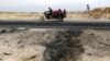 An Afghan family ride on a bike past the site of a car bomb attack where U.S. soldiers were killed near Bagram air base, Afghanistan, April 9, 2019.