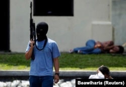 Seorang teroris tiruan memegang senapan di dekat "warga sipil yang ditahan" dalam latihan anti-teror di markas pasukan khusus polisi di Depok, Jawa Barat, 9 Maret 2010. (Foto: REUTERS/Beawiharta)