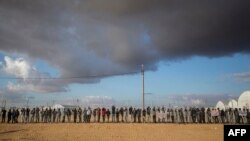 FILE - African asylum seekers, who entered Israel illegally via Egypt, lean at the fence of the Holot detention center in Israel's southern Negev Desert, on Feb. 17, 2014 as they join other migrants who came to protest outside the detention facility. 
