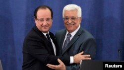 Palestinian President Mahmoud Abbas (R) and his French counterpart Francois Hollande embrace during a joint news conference in the West Bank city of Ramallah, Nov. 18, 2013. 
