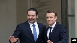 French President Emmanuel Macron, right, poses for photographers with Lebanon's Prime Minister Saad Hariri prior to their meeting at the Elysee Palace in Paris, Saturday, Nov. 18, 2017.
