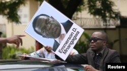 A protester holds a poster showing support for ousted Zimbabwean Vice President Emmerson Mnangagwa, in Harare, Zimbabwe, Nov. 18, 2017.