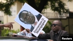 A protester holds a poster showing support for ousted Zimbabwean Vice President Emmerson Mnangagwa, in Harare, Zimbabwe, Nov. 18, 2017.
