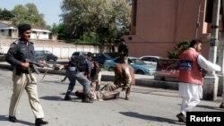Security officials carry away an injured man from the site of a bomb blast in Peshawar, March 29, 2013.