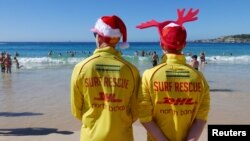 Simon, left, and Victor volunteer life guards from North Bondi Surf Life Saving Club, keep an eye on swimmers enjoying Christmas day on Bondi Beach, Sydney, Dec. 25, 2018. Australia looks set to sweat through one of its hottest Decembers ever.