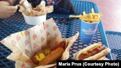 A person eats hotdogs and french fries at a Washington Nationals baseball game in Washington, DC.