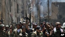 In this photo taken during a government-organized tour, Syrian soldiers celebrate after they regained control of the district of Midan, in the southern part of Damascus, Syria, Friday, July 20, 2012. Syrian troops and tanks on Friday drove rebels from a D