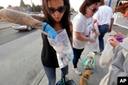 Safe Night Access Project in Seattle volunteers Justice Rivera, left, and Laura LeMoon pass out supplies to people on the street while providing harm reduction services to sex workers, Aug. 9, 2018. Recent crackdowns targeting the sex-for-hire industry have reduced the number of commercial ads on the internet and helped fight online trafficking. But activists and police say the efforts may have landed women and girls back on the streets, where dangers also lurk.