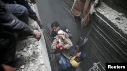 Syria Civil Defense members help an unconscious woman from a shelter in the besieged town of Douma, Eastern Ghouta, Damascus, Syria, Feb. 22, 2018. 