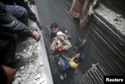 Syria Civil Defence members help an unconscious woman from a shelter in the besieged town of Douma, Eastern Ghouta, Damascus, Syria, Feb. 22, 2018.