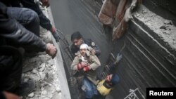 Syria Civil Defence members help an unconscious woman from a shelter in the besieged town of Douma, Eastern Ghouta, Damascus, Syria, Feb. 22, 2018. 