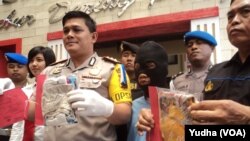 Polisi menujukkan tersangka pedofilia (baju tahanan warna biru--tengah) dan barang bukti sejumlah pakaian anak korban pedofil (Foto: VOA/Yudha)