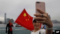 Para pendukung China berswafoto dengan latar bendera China untuk mendukung polisi dan gerakan anti kekerasan dalam unjuk rasa di Hong Kong, Sabtu, 17 Agustus 2019. (Foto: AP)