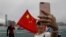 Para pendukung China berswafoto dengan latar bendera China untuk mendukung polisi dan gerakan anti kekerasan dalam unjuk rasa di Hong Kong, Sabtu, 17 Agustus 2019. (Foto: AP)