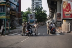 Policías indios revisan las credenciales de ciudadanos mientras hacen cumplir un confinamiento de fin de semana para contener la propagación del coronavirus en Kochi, estado de Kerala, en India, el domingo 2 de mayo de 2021.