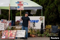 Boeing worker Riley Nelson holds a sign at a picket line near the entrance to a Boeing production facility in Renton, Wash., Oct. 11, 2024.