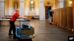 Workers prepare booths at a polling station in Lyon, central France, April 22, 2017. The first of two rounds of voting in France proper will take place on April 23. 