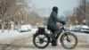 Un ciclista para por la avenida 13th después de que una tormenta invernal bajara la temperatura máxima diurna y dejara nieve en la calle el lunes 20 de enero de 2025 en Denver.