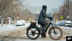 Un ciclista para por la avenida 13th después de que una tormenta invernal bajara la temperatura máxima diurna y dejara nieve en la calle el lunes 20 de enero de 2025 en Denver.