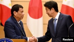 Philippines President Rodrigo Duterte shakes hands with Japanese Prime Minister Shinzo Abe at the end of their signing ceremony and joint remarks at Abe's official residence in Tokyo, Oct. 30, 2017.