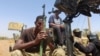 (FILE) A member of Sudanese Armed Forces holds his weapon as he and others sit on an army vehicle in Omdurman, Sudan, March 9, 2024.