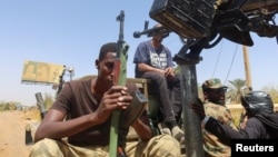 (FILE) A member of Sudanese Armed Forces holds his weapon as he and others sit on an army vehicle in Omdurman, Sudan, March 9, 2024.