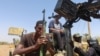 FILE - A member of Sudanese armed forces holds his weapon as he and others sit on an army vehicle in Omdurman, Sudan, March 9, 2024.