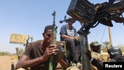 FILE - A member of Sudanese armed forces holds his weapon as he and others sit on an army vehicle in Omdurman, Sudan, March 9, 2024.