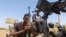 FILE - A member of Sudanese armed forces holds his weapon as he and others sit on an army vehicle in Omdurman, Sudan, March 9, 2024.