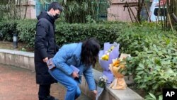 مردم با قرار دادن گل پشت بیمارستان مرکزی ووهان به دکتر لی ونلیانگ، پزشک فقید افشاگر ویروس کرونای نوپدید، ادای احترام کردند - ۶ فوریه ۲۰۲۱ 