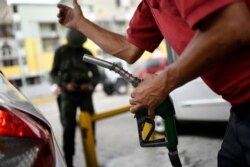 Un trabajador sostiene una bomba de gasolina en una estación de servicio de la compañía petrolera estatal PDVSA en Caracas, Venezuela, el lunes 25 de mayo/2020.