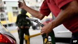 Un trabajador sostiene una bomba de gasolina en una gasolinera de la petrolera estatal PDVSA en Caracas, Venezuela. Mayo 25, 2020. Foto: AP.