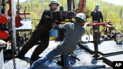 FILE - Workers move a section of well casing into place at a Chesapeake Energy natural gas well site near Burlington, Pennsylvania, April 23, 2010.