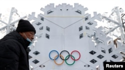 A worker walks in front of an installation with the Olympic Rings on January 19, 2022, near The National Stadium, also known as the Bird's Nest, where the opening and closing ceremonies of Beijing 2022 Winter Olympics will be held. (Carlos Garcia Rawlins/Reuters)