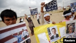 Residents who face eviction from their homes display signs with pictures of U.S. President Barack Obama and Secretary of State Hillary Clinton, as they ask for help in protecting their rights during a protest ahead of their visit in Phnom Penh November 18