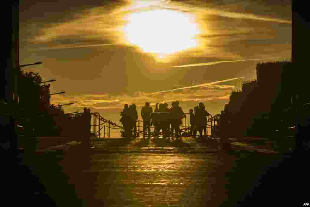 People watch the sunrise under the Arc de Triomphe (Arch of Triumphal) at the end of the Champs Elysees Avenue, in Paris, France.