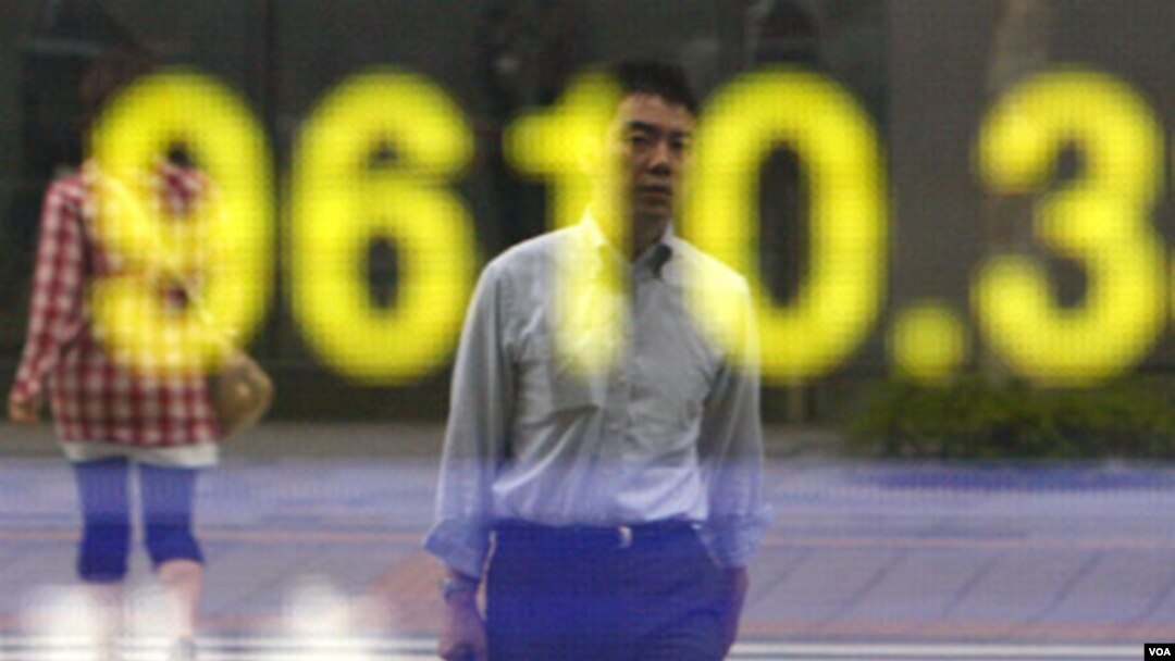 Seorang warga mengamati papan elektronik indeks Nikkei di Tokyo. Pasar-pasar Asia mengalami kenaikan hari Senin (15/8).