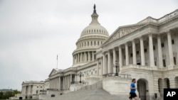 A man wearing a mask jogs past the U.S. Capitol Building, April 28, 2020, in Washington.