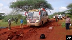 Kenyan security forces and others gather around the scene on an attack on a bus about 50 kilometers (31 miles) outside the town of Mandera, near the Somali border in northeastern Kenya, Nov. 22, 2014.