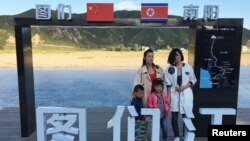 Tourists pose at the border with North Korea in Tumen, China, Aug. 30, 2017. China reported seven months of falling imports from North Korea.